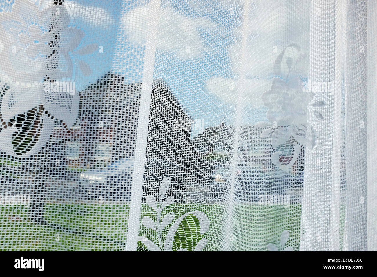 Ein Suburban Home Fenster Szene durch Gardinen im Sommer. Stockfoto