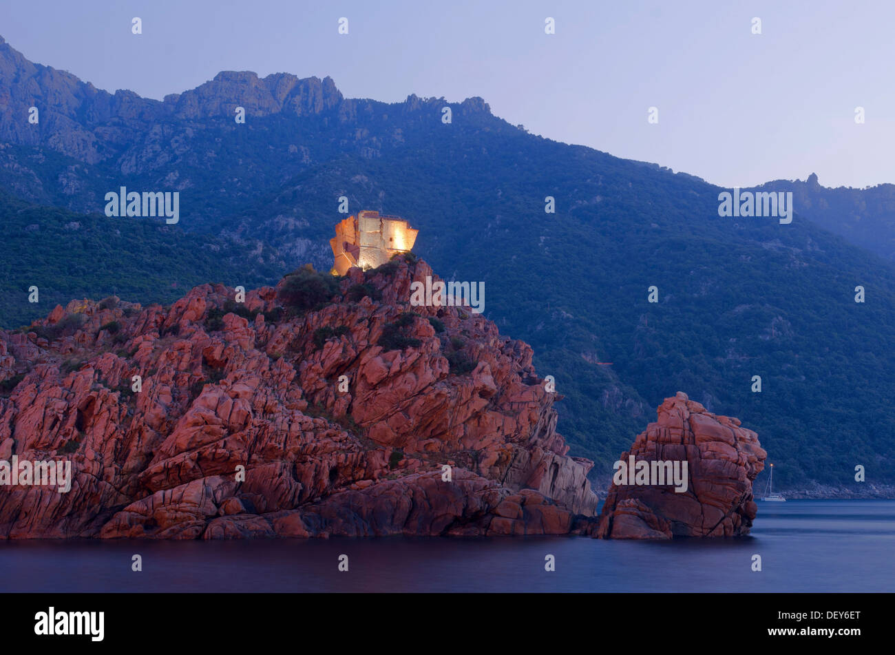 Das Flutlicht genuesischen Turm von Porto auf einem felsigen Hügel und den Golf von Porto zur blauen Stunde, in der Abenddämmerung, Guaita, Porto Stockfoto