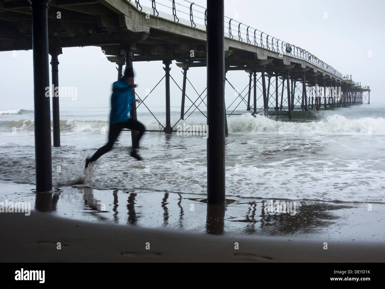 Flut tränkt Jogger unter Pier am Saltburn am Meer, North Yorkshire, Stockfoto