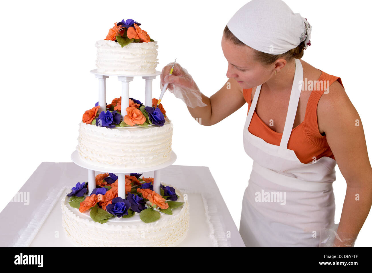 Baker-Dame mit einem weißen Halstuch zu einer endgültigen Hochzeitstorte berührt, Kuchen Fondant Rüschen auf der Seite hat und dekoriert Stockfoto