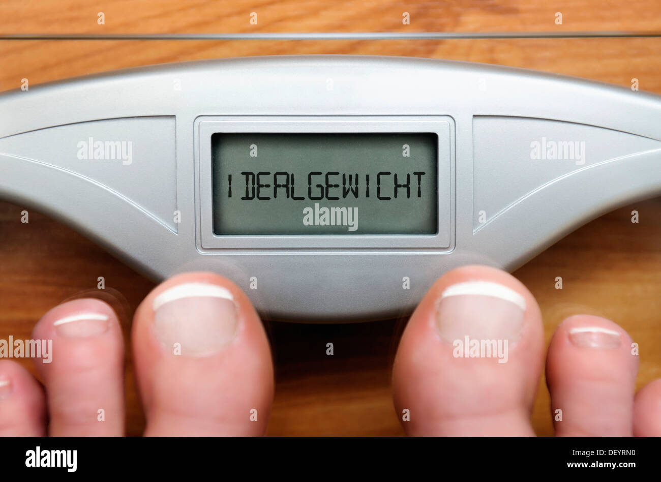 Füße auf Waagen mit Digitalanzeige und der Schriftzug "Idealgewicht", Deutsch für "Idealgewicht" Stockfoto