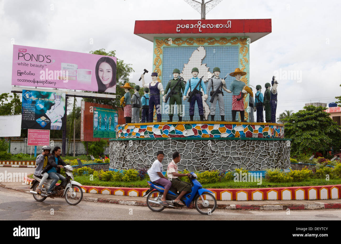Leute fahren von Statuen an einem Kreisverkehr in Mawlamyine. Stockfoto