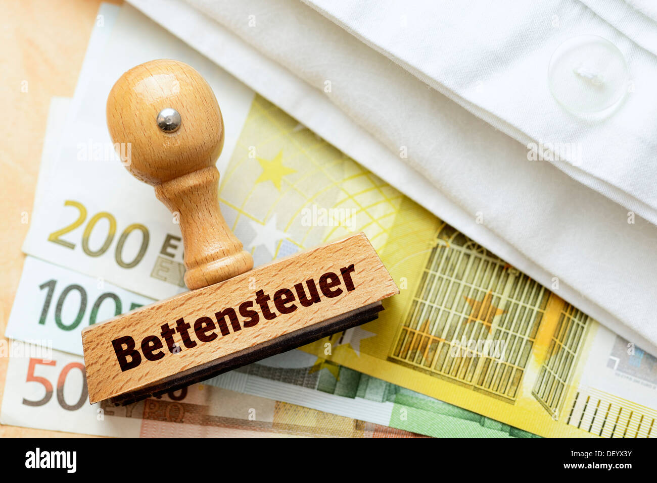 Stempel mit dem Begriff "Bettensteuer" Deutsch für "Bettensteuer" für Euro-Banknoten und ein Bettlaken Stockfoto