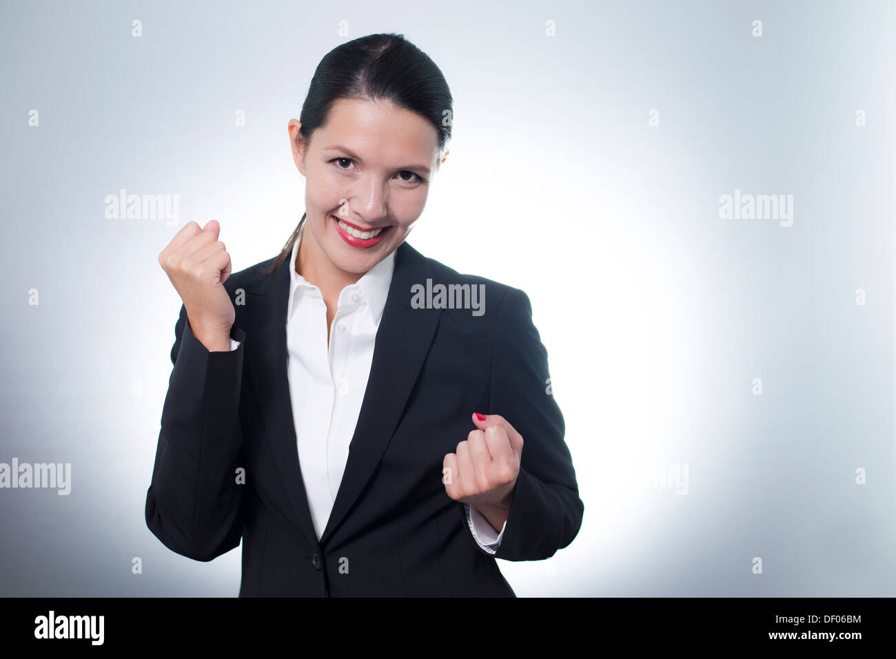 Schöne jubelnde junge Geschäftsfrau jubeln mit einem strahlenden begeisterten Lächeln auf ihrem Gesicht, als sie einen Erfolg feiert Stockfoto
