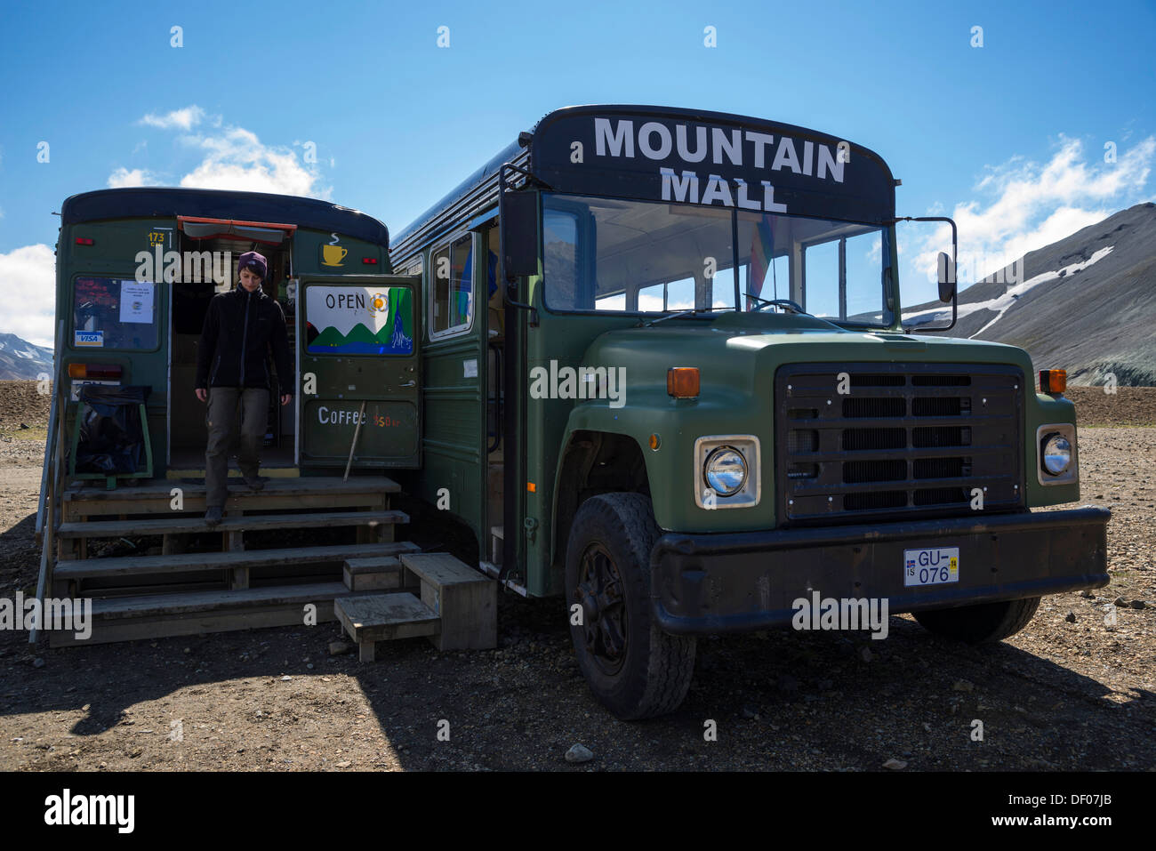 Frau auf der Treppe zu einem Geschäft in einem umgebauten Bus, Campingplatz, Landmannalaugar Campingplatz Fjallabak Naturschutzgebiet Stockfoto