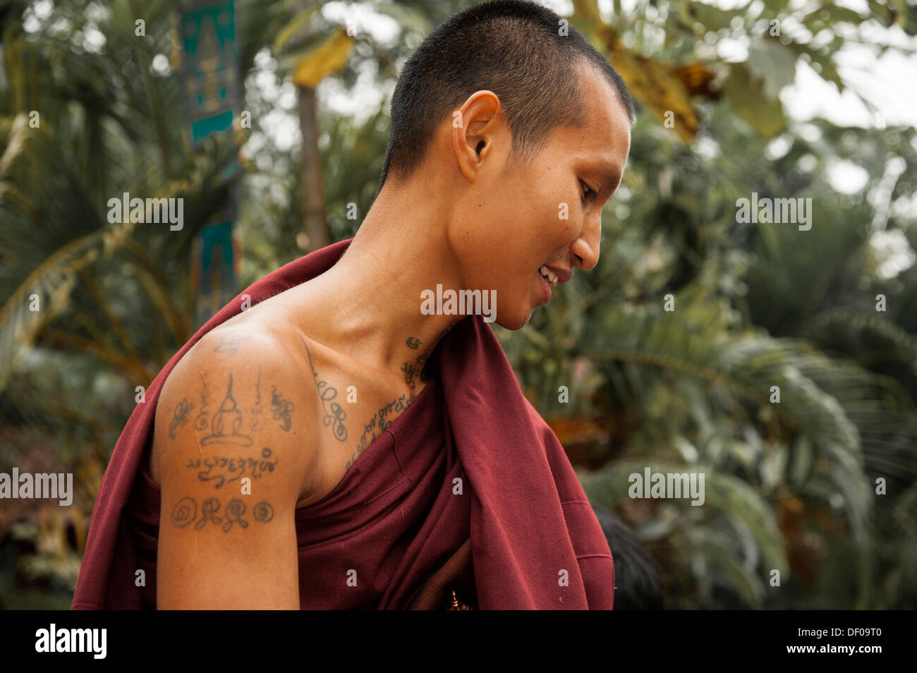 Lächelnde buddhistischer Mönch mit Tattoos Almosen am Morgen, Porträt, Tempel und Kloster Wat Phra Archa Thong oder Stockfoto