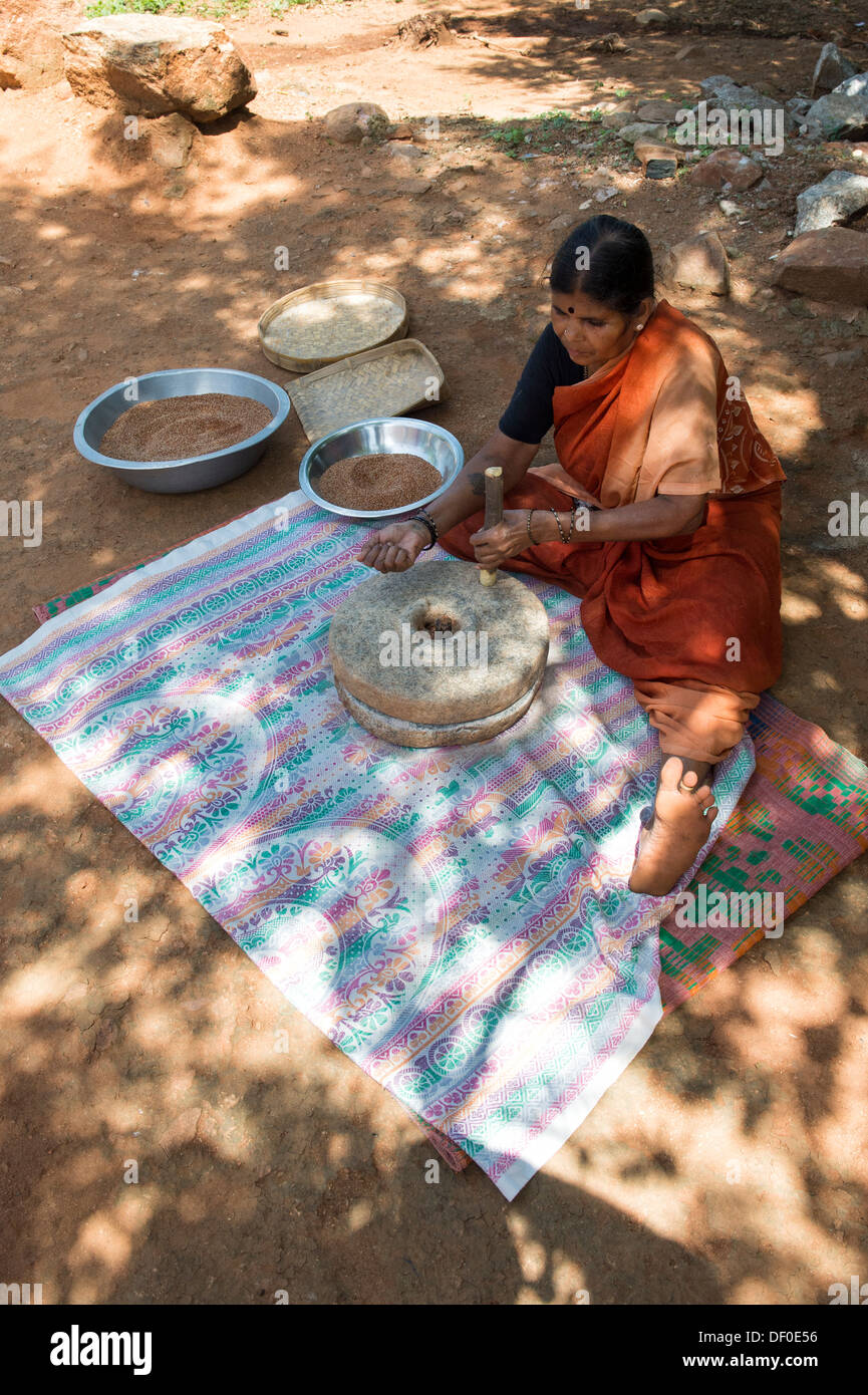 Indische Dorf Frau mit Mahlsteinen Steinen Fingerhirse Samen mahlen / Ragi-Hirse Samen zu Ragi-Hirse-Mehl. Andhra Pradesh. Indien Stockfoto