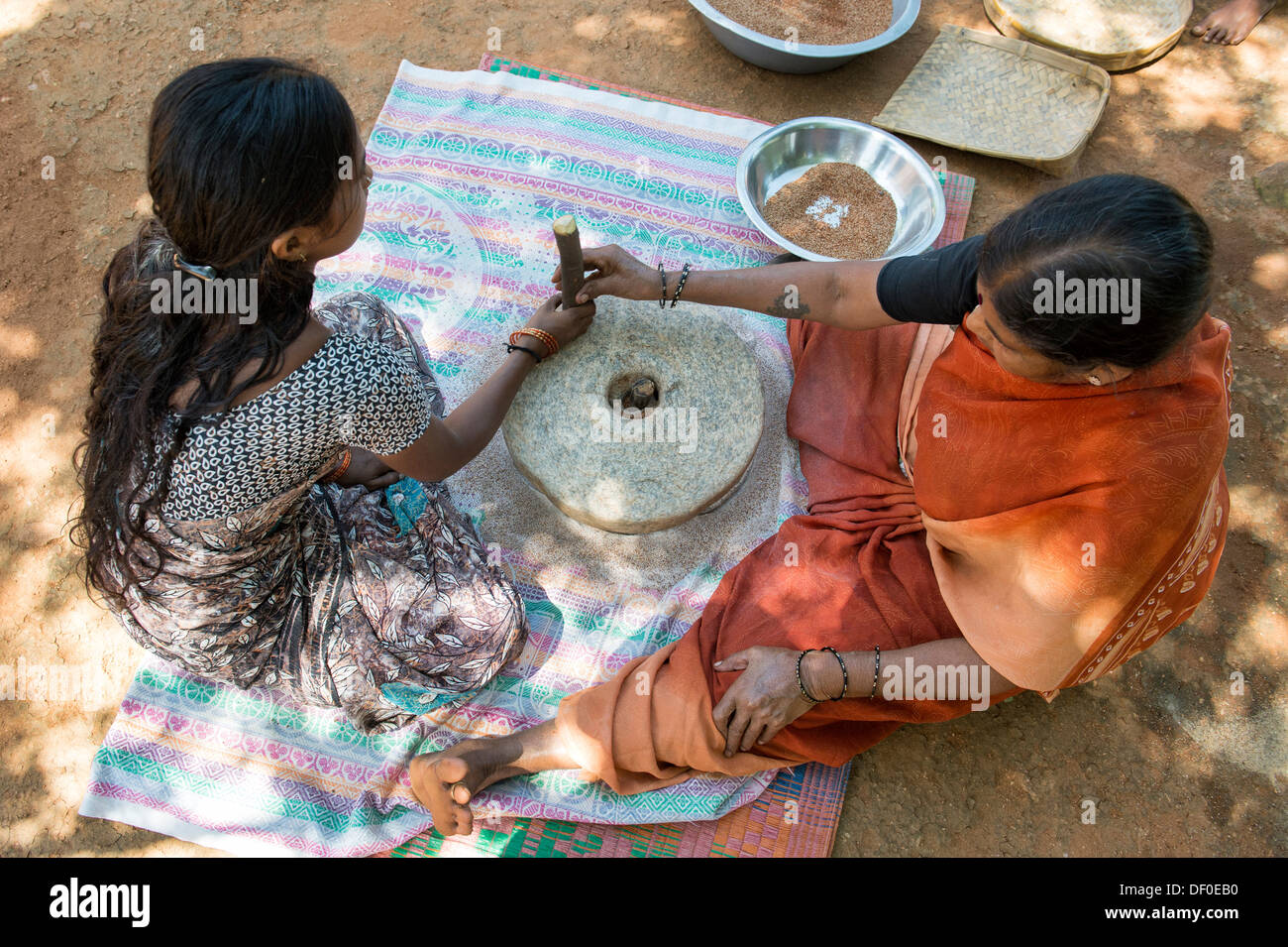 Ländliche Indianerdorf Frauen mit Mahlsteinen Steinen Fingerhirse Samen mahlen / Ragi-Hirse Samen zu Ragi-Hirse-Mehl. Andhra Pradesh. Indien Stockfoto