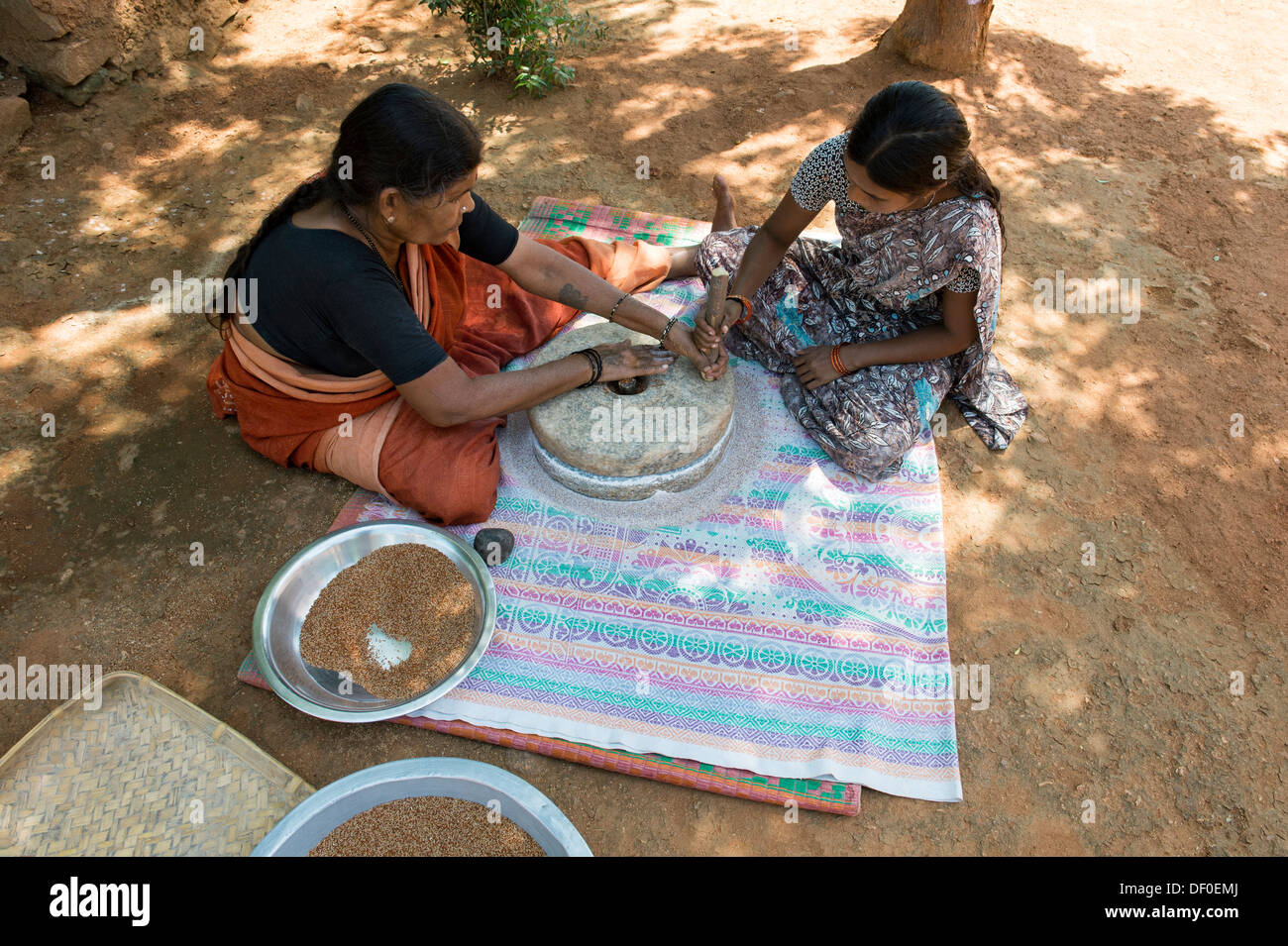 Ländliche Indianerdorf Frauen mit Mahlsteinen Steinen Fingerhirse Samen mahlen / Ragi-Hirse Samen zu Ragi-Hirse-Mehl. Andhra Pradesh. Indien Stockfoto