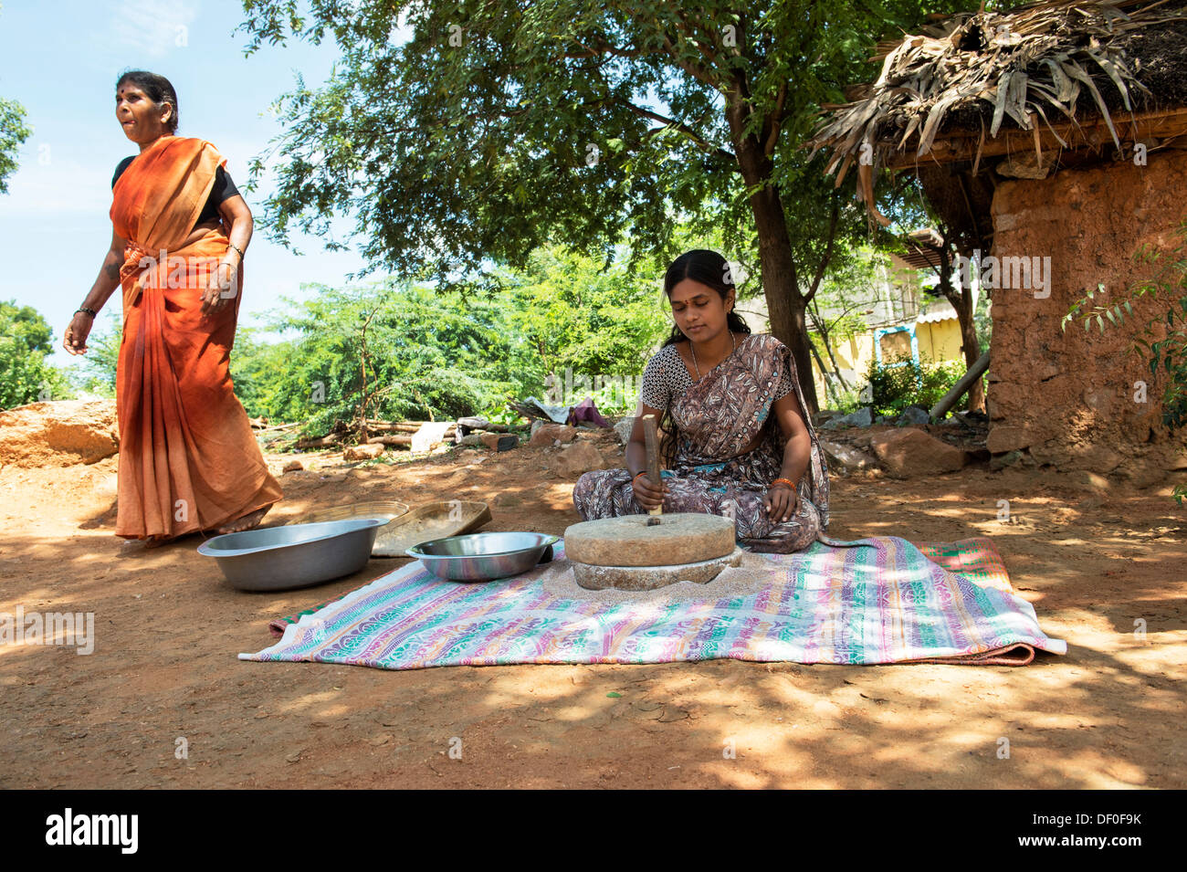 Ländliche Indianerdorf Frauen mit Mahlsteinen Steinen Fingerhirse Samen mahlen / Ragi-Hirse Samen zu Ragi-Hirse-Mehl. Andhra Pradesh. Indien Stockfoto