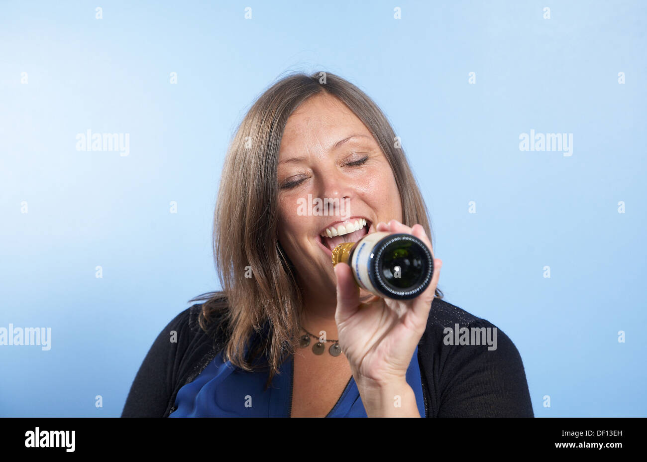 Frau singt, mit einer Flasche als vorgeben Mikrofon. Stockfoto