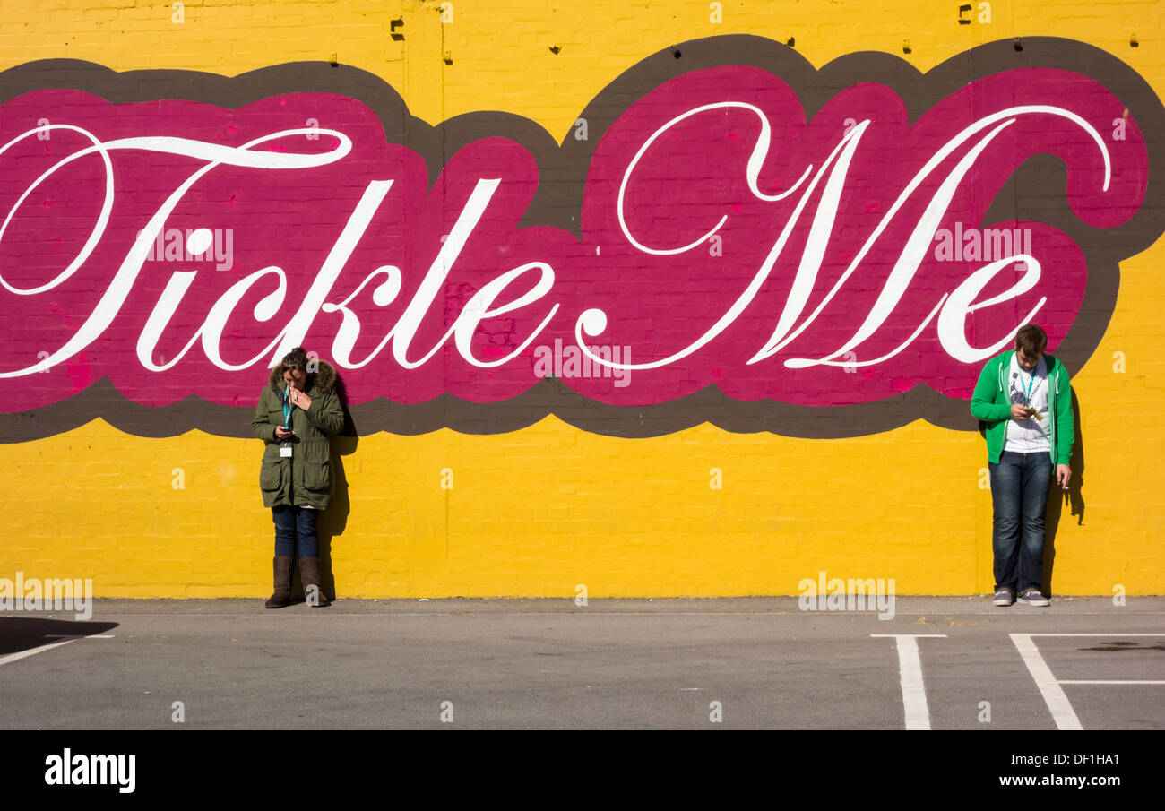 Zwei Personen, die Mobiltelefone außerhalb des Büros betrachten. GROSSBRITANNIEN. Könnte für soziale Distanzierung, Coronavirus, Selbstisolierungskonzept verwendet werden... Stockfoto