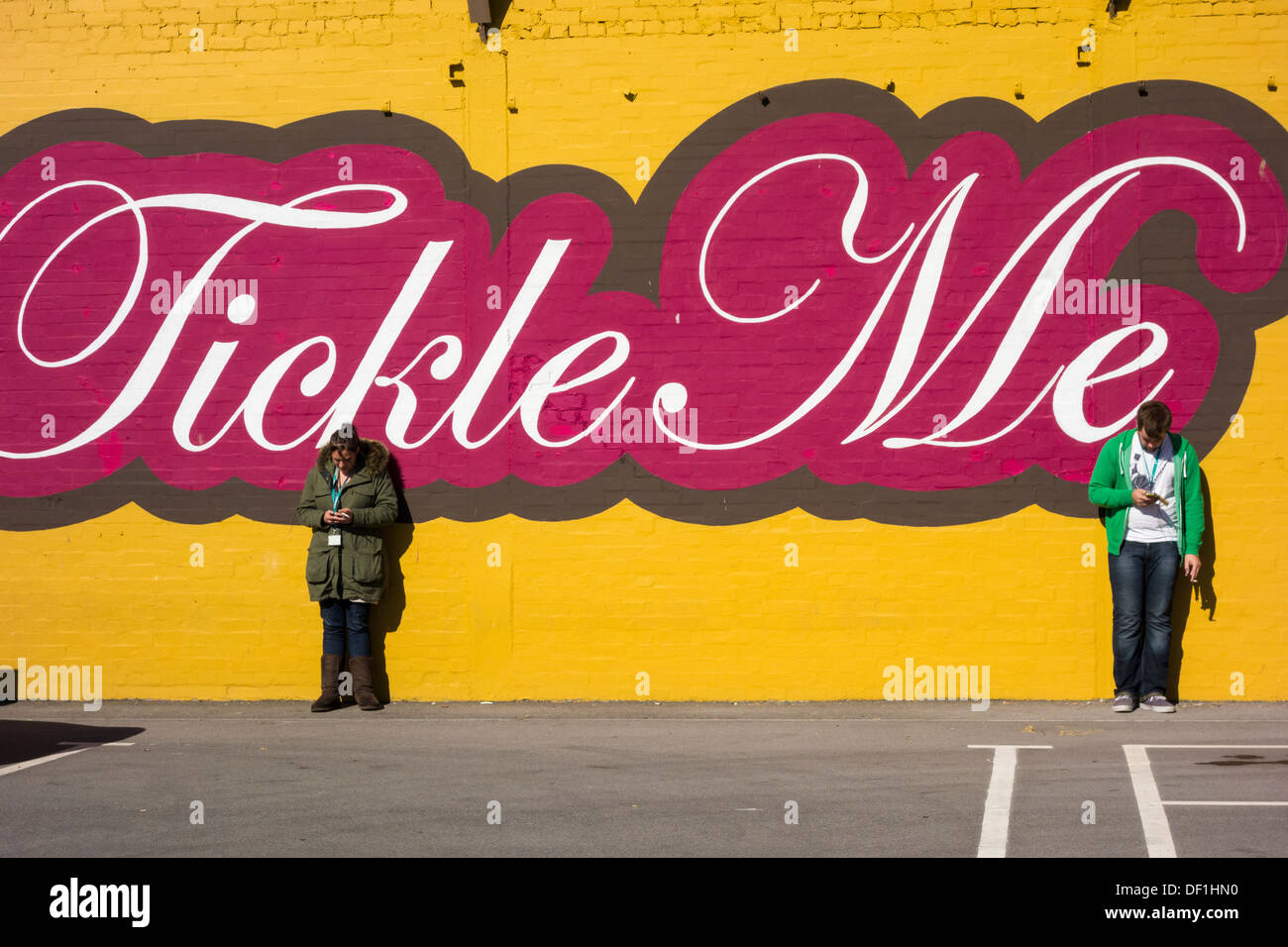 Zwei Personen, die Mobiltelefone außerhalb des Büros betrachten. GROSSBRITANNIEN. Könnte für soziale Distanzierung, Coronavirus, Selbstisolierungskonzept verwendet werden. Stockfoto