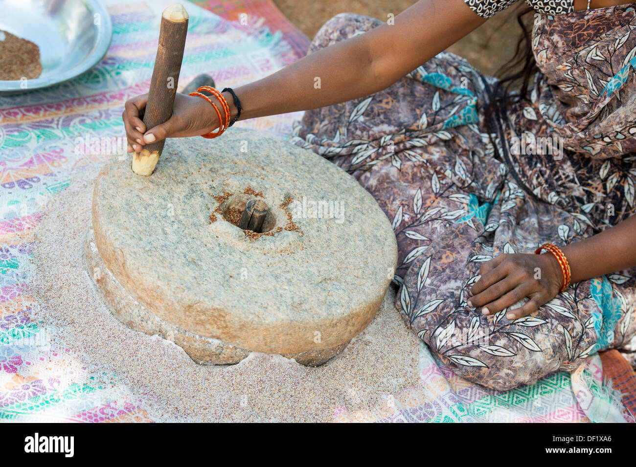 Indische Dorf Frau mit Mahlsteinen Steinen Fingerhirse Samen mahlen / Ragi-Hirse Samen zu Ragi-Hirse-Mehl. Andhra Pradesh. Indien Stockfoto