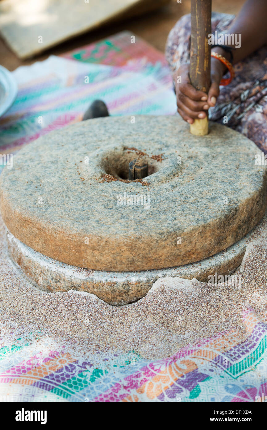 Indische Dorf Frau mit Mahlsteinen Steinen Fingerhirse Samen mahlen / Ragi-Hirse Samen zu Ragi-Hirse-Mehl. Andhra Pradesh. Indien Stockfoto