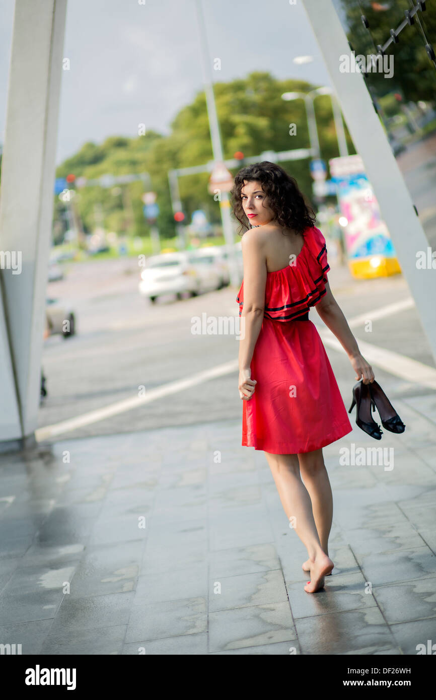 Frau im roten Kleid, die rückblickend über die Schulter Stockfoto