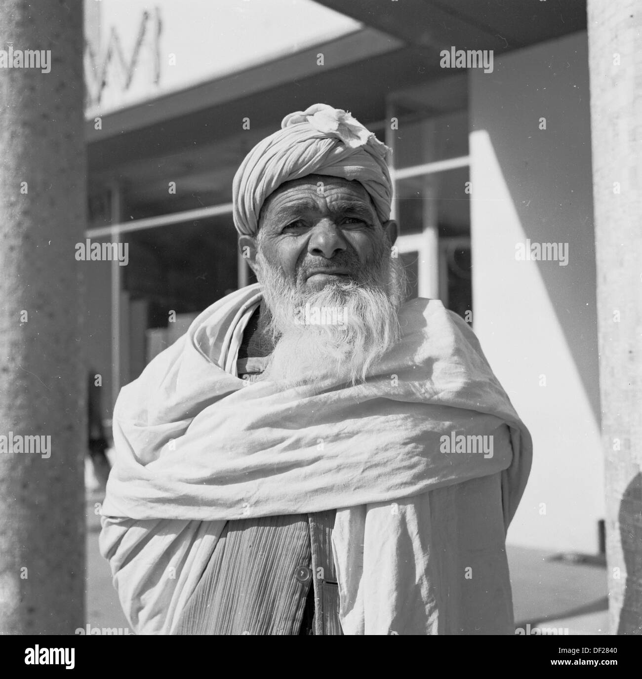 Historisches Bild aus den 1950er Jahren von J Allan Cash eines älteren bärtigen afghanischen Mannes in Kabul, Afghanistan, umwickelt mit einem traditionellen Baumwoll- oder Stoffgewand um ihn herum und mit Bart und Kopfschmuck. Stockfoto