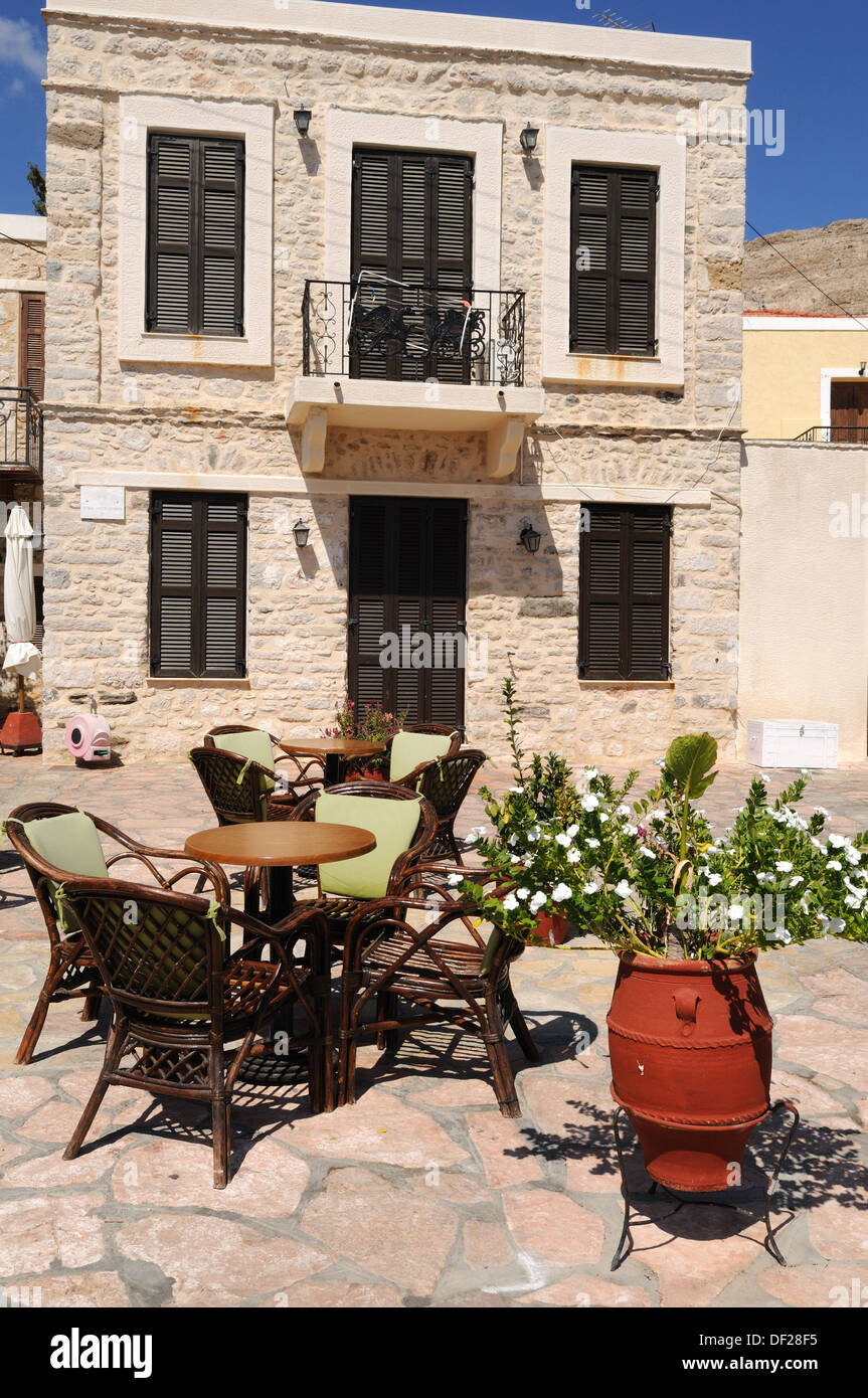 Ein typisches Halki Chalki-Haus mit Tischen und Stühlen und einen Topf mit Blumen außerhalb der Dodekanes-Griechenland Stockfoto