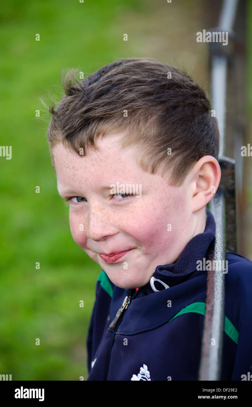 Irische Boy mit schelmischen Lächeln gelehnt Zaun Geländer Blick in die Kamera, County Cork, Irland. Stockfoto