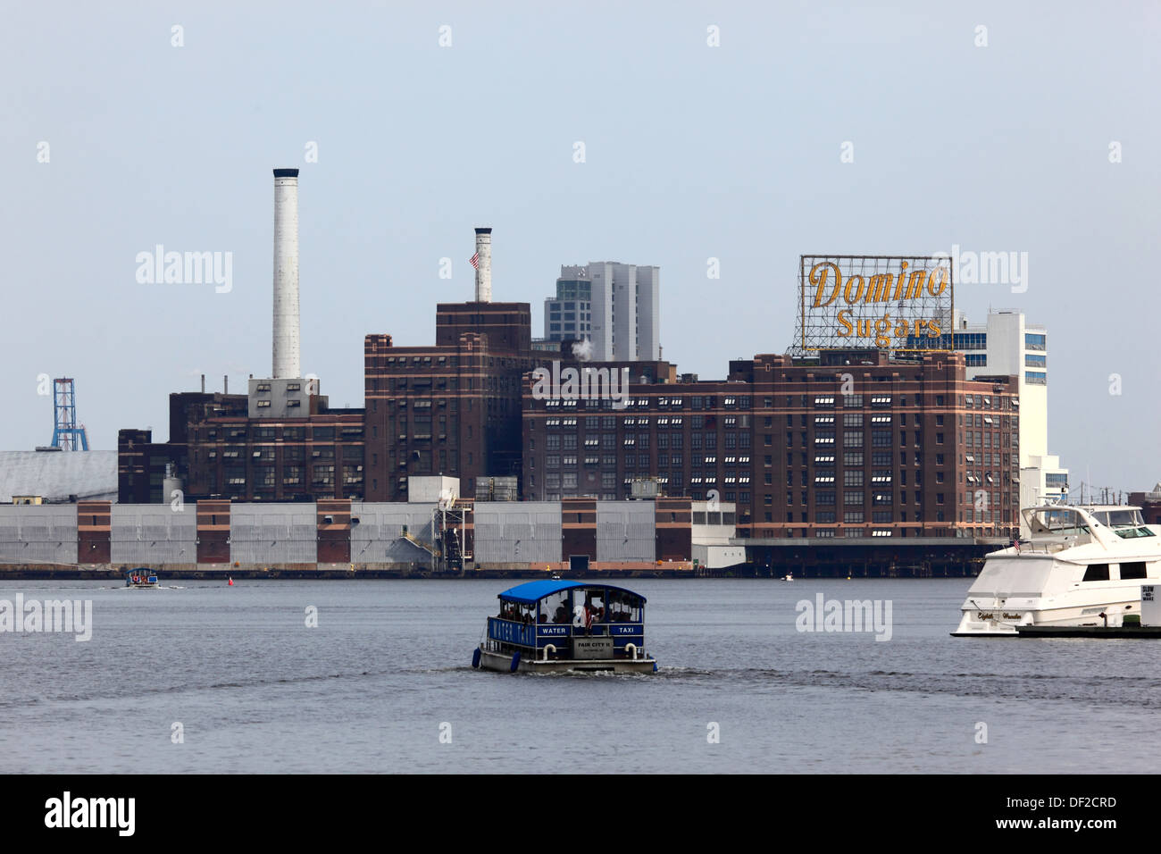 Wasser-Taxi überqueren Innenhafen, Domino Zucker Fabrikgebäude in Locust Punkt im Hintergrund, Baltimore, Maryland, USA Stockfoto