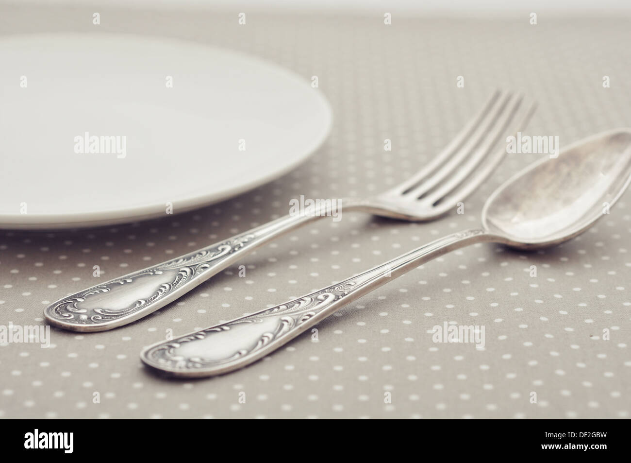 Weißen Teller, Gabel und Löffel auf leichte Polka Dot Hintergrund. Stockfoto