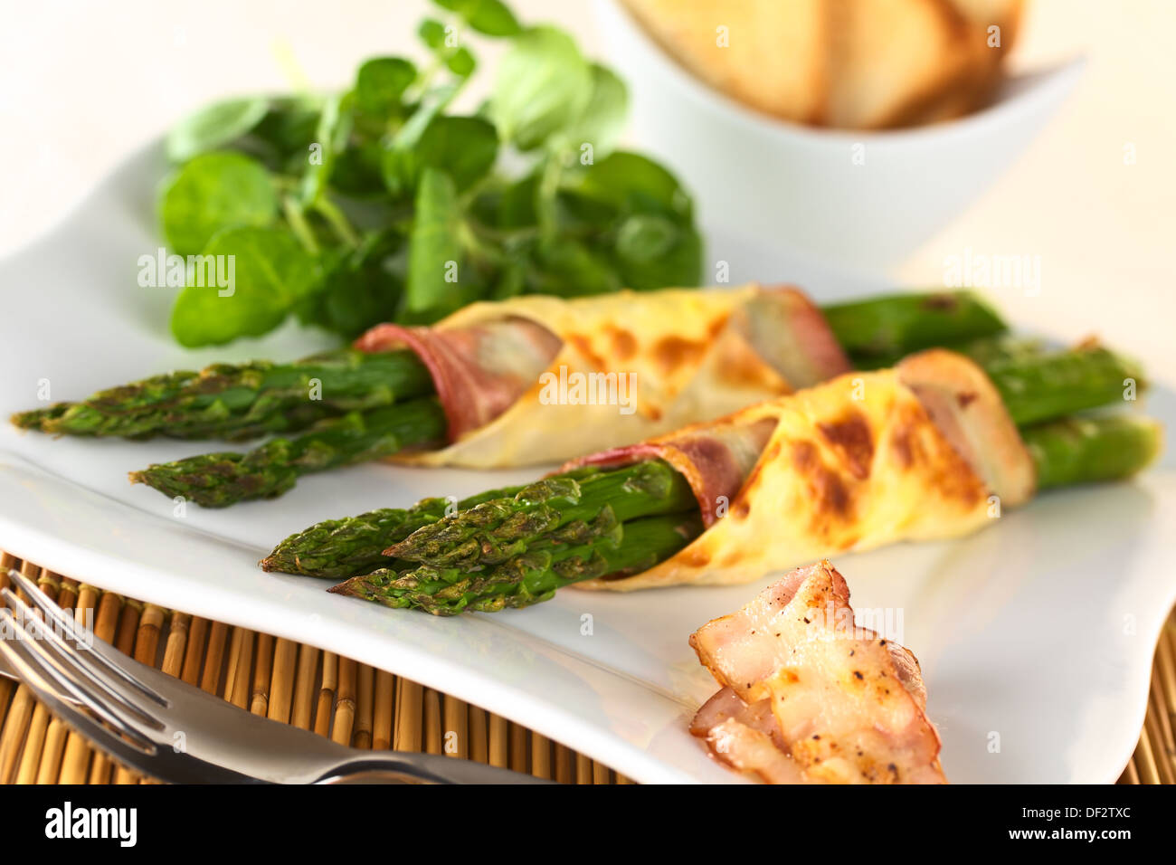 Gebackene Grünspargel eingewickelt in Speck und Wan-Tan-Teig (selektiven Fokus, Fokus auf die Spargelspitzen des ersten Bundles) Stockfoto