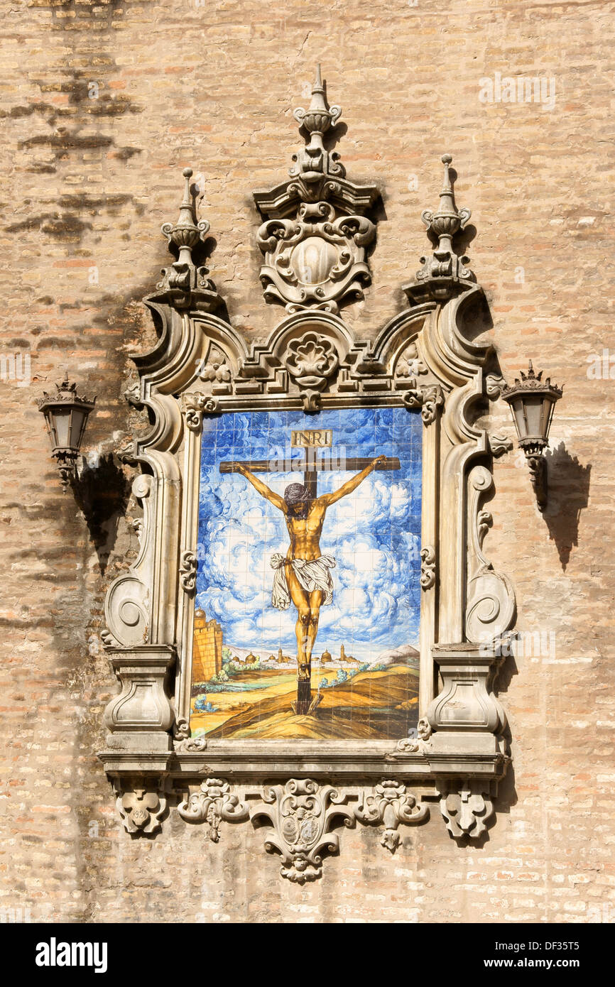 Azulejo zeigt Jesus am Kreuz auf einer Außenwand der Kirche der Mariä Verkündigung (Iglesia De La Anunciación) in Sevilla. Stockfoto