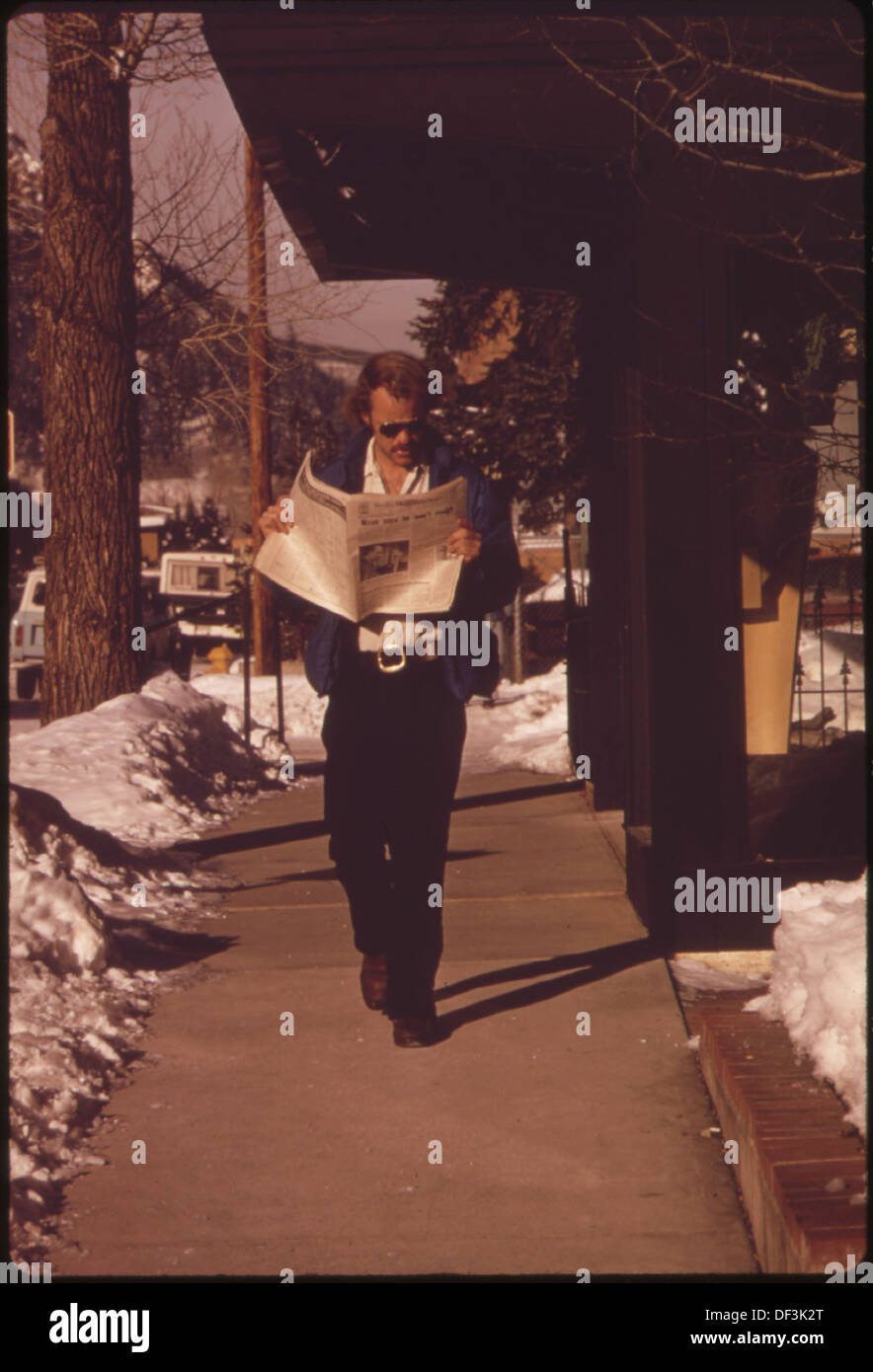 Das Foto zeigt jemanden, der die Nachrichten aufholt und wahrscheinlich eine Zeitung oder Zeitschrift liest. Diese Aktion stellt eine Ära des traditionellen Nachrichtenkonsums dar, bevor die digitalen Medien sich verbreiteten. Stockfoto