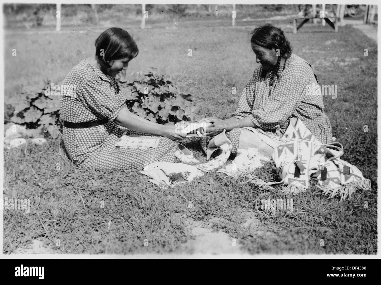 Eine ältere Frau lehrt ihrer Enkelin die Kunst der Perlenarbeit und gibt kulturelle und künstlerische Traditionen an die nächste Generation weiter, was die Bedeutung von Handwerkskunst im Familienerbe widerspiegelt. Stockfoto