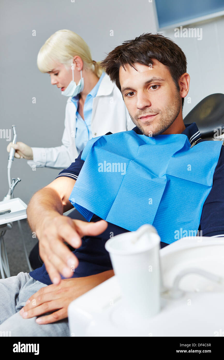 Mann beim Zahnarzt nach seiner Zahnbehandlung für Tasse Wasser zu erreichen Stockfoto