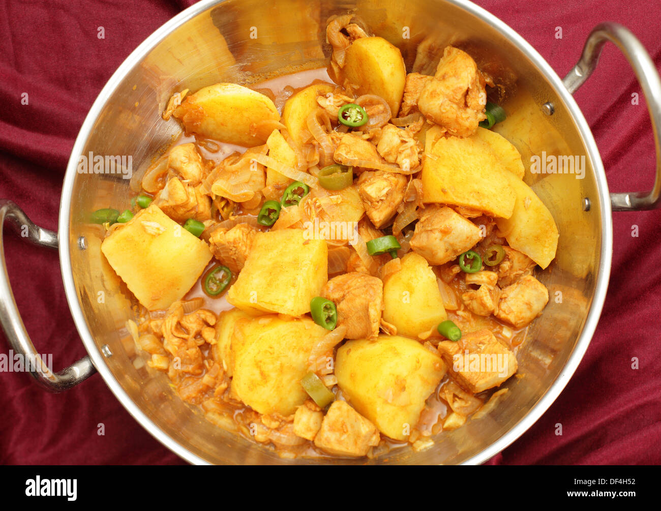 Ein Vindaloo Hühnchen und Kartoffeln curry, gekochte Balti-Stil in einem Kadai (Karahi) Kochtopf, garniert mit in Scheiben geschnittenen Chilis Stockfoto