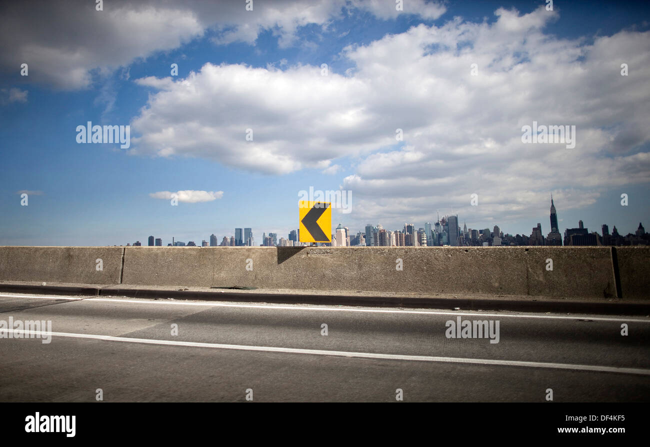 Pfeil-Symbol auf der Autobahn mit New Yorker Skyline im Hintergrund Stockfoto