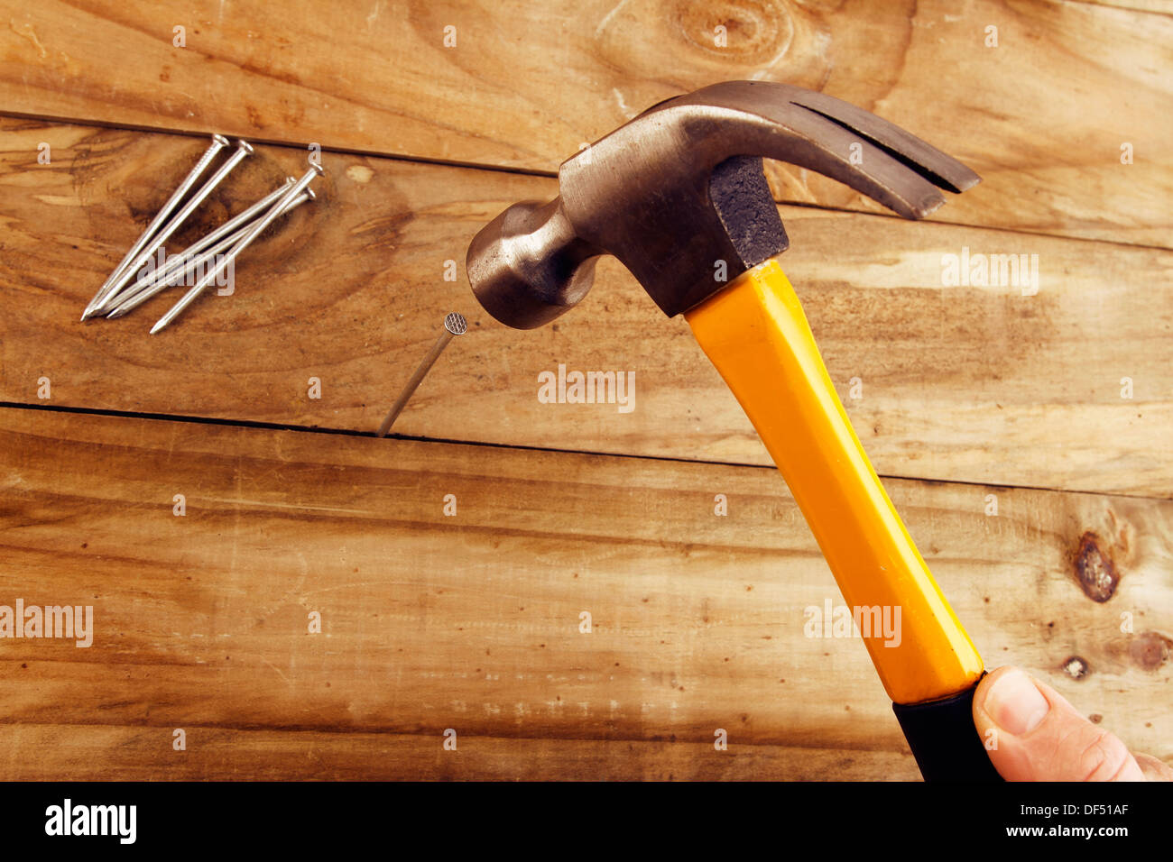 Ein Baumeister Hammer einen Nagel ins Holz Stockfoto
