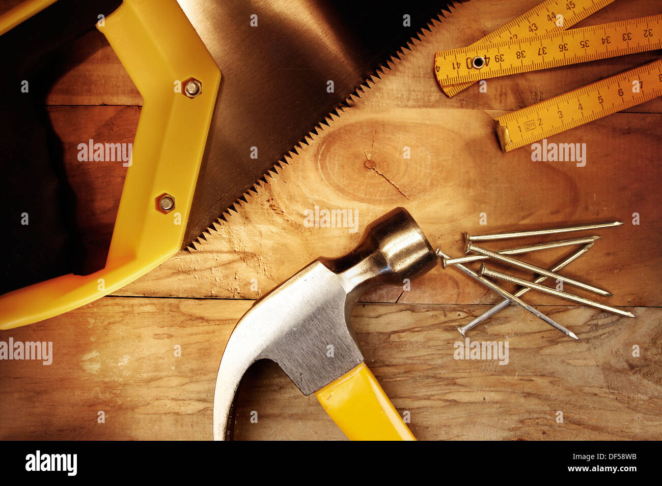 Hammer, Nägel, Lineal und Säge auf Holz Stockfoto