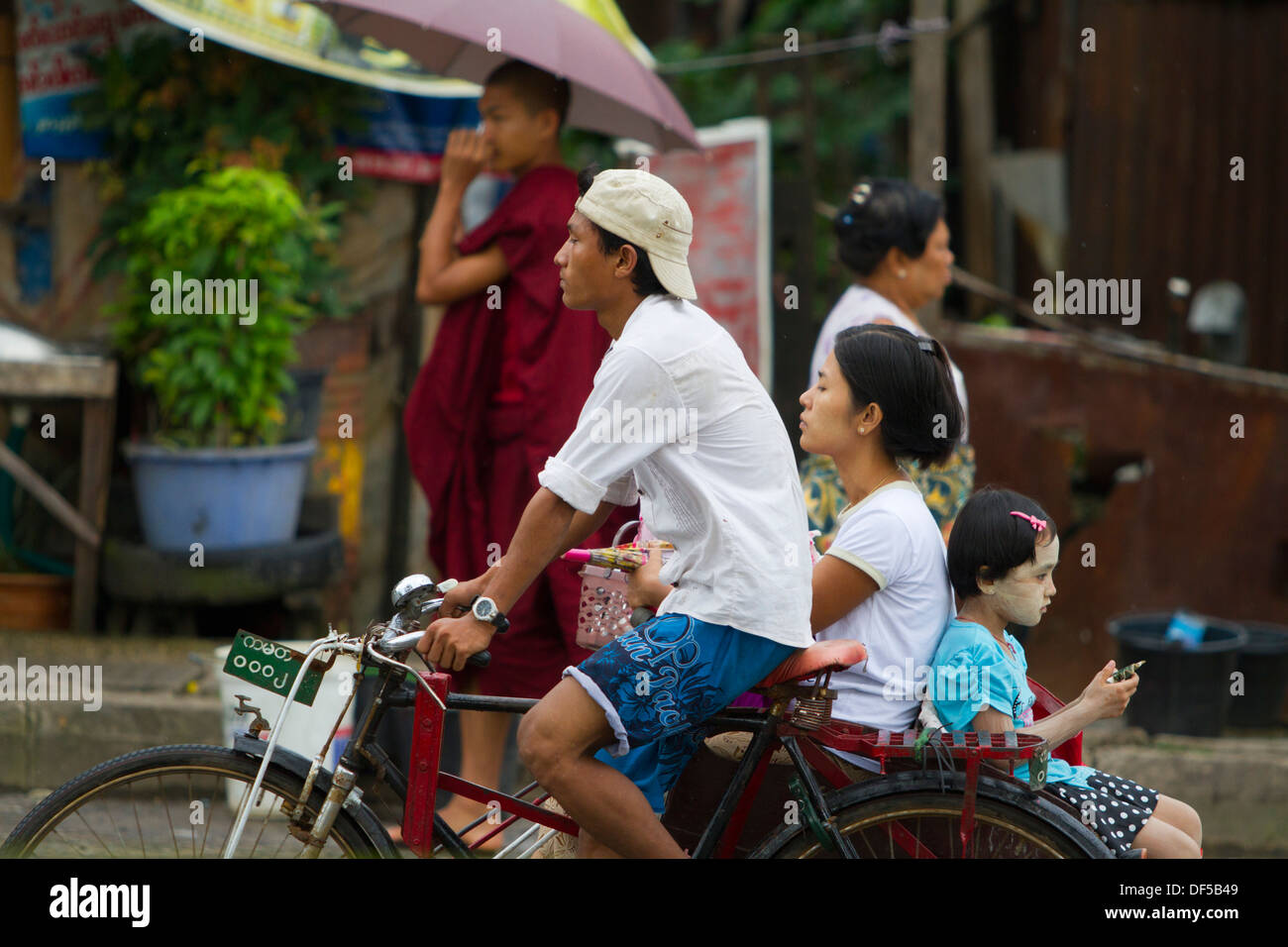 Personen fahren in einer Rikscha in der Nähe eines Bahnhofs in Yangon, Birma. Stockfoto