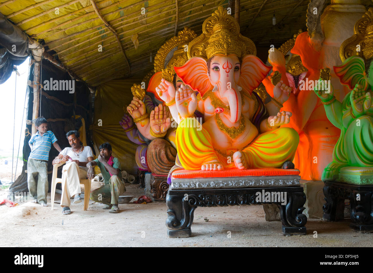 Arbeiter in Indien für den Geburtstag von Lord Ganesha fertigen Idole in behelfsmäßigen Fabriken am Straßenrand sitzen. Stockfoto
