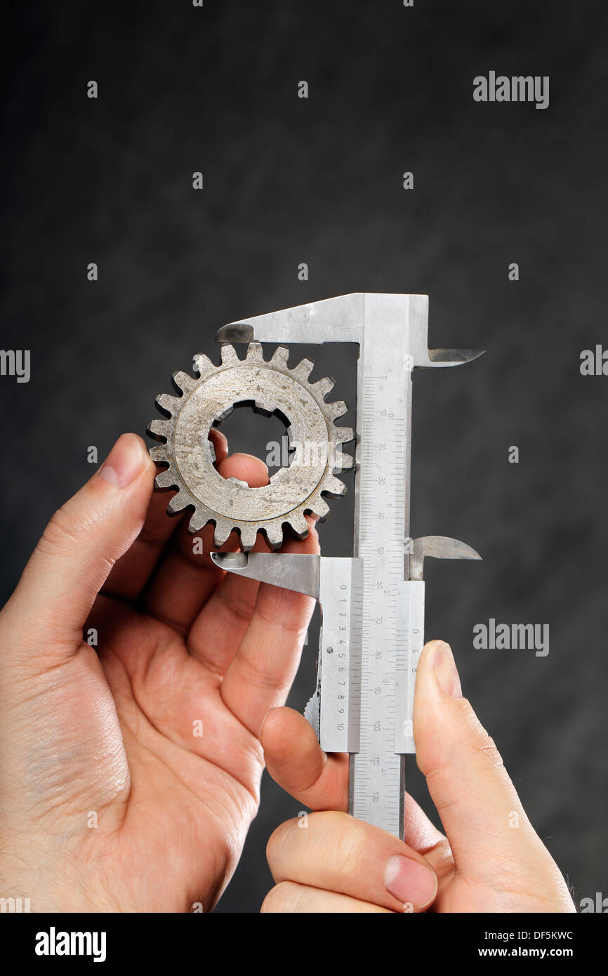 Messung des Durchmessers der alten Zahnradbahn mit Vernier Bremssattel Mann. Stockfoto