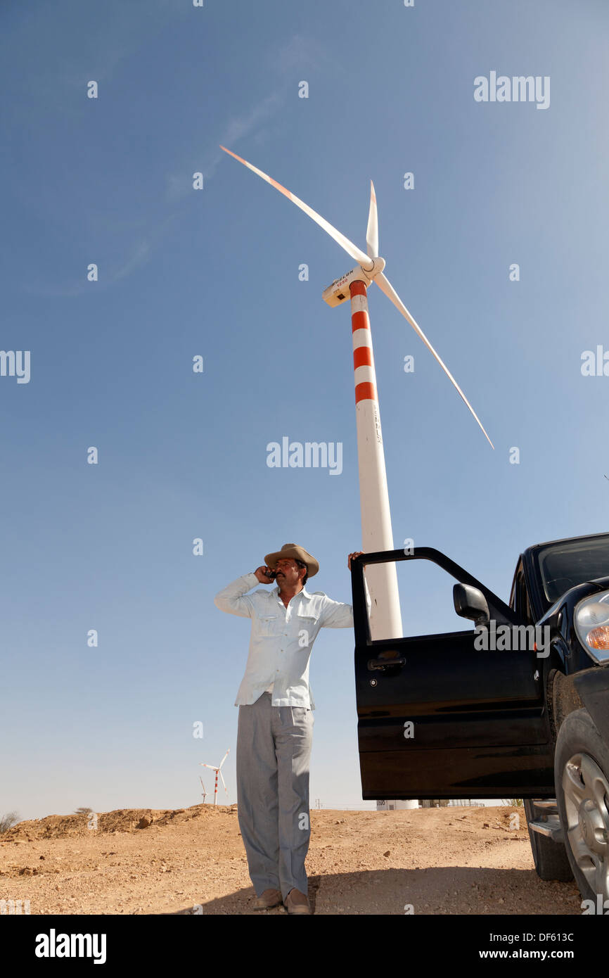 Indien, Rajasthan, Thar-Wüste, Ingenieur stehen von Windkraftanlagen mit Handy Stockfoto