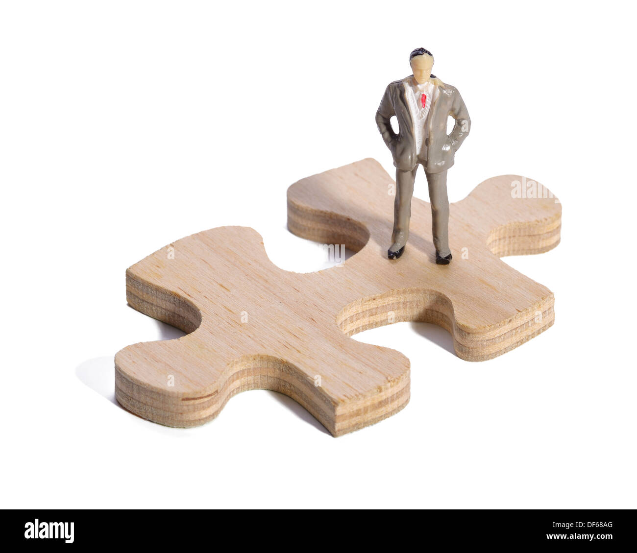 Kunststoff-Business-Mann stehend auf einem hölzernen Puzzleteil Stockfoto