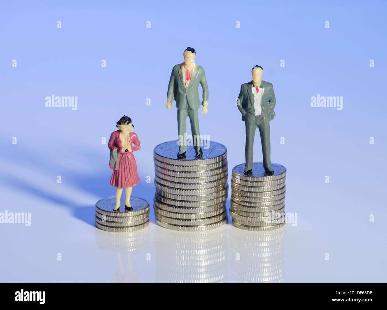 Mini-Kunststoff Männer und eine Frau stehen auf Haufen Geld Stockfoto