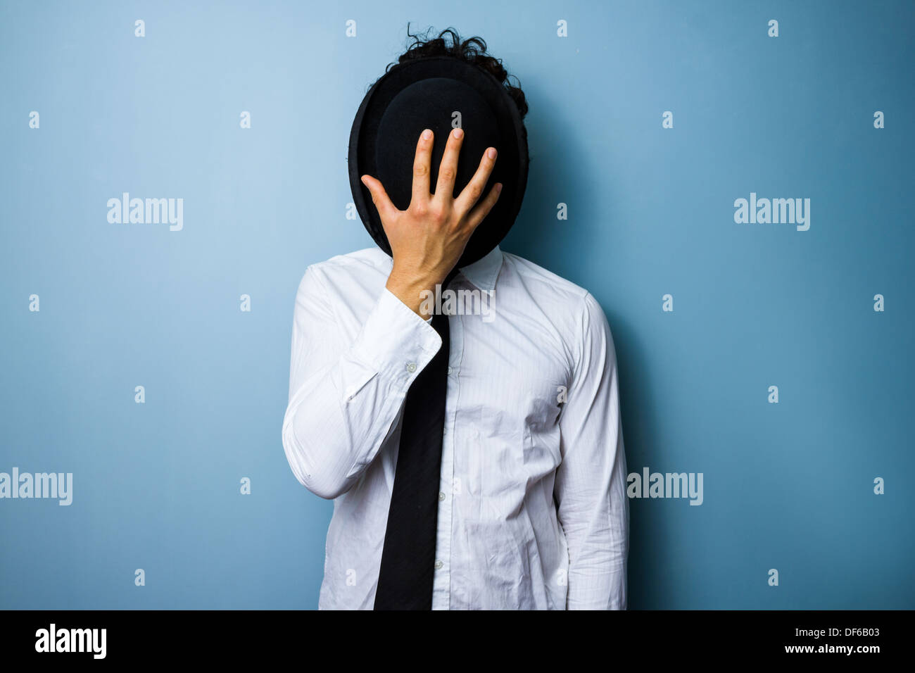 Junger Mann versteckt sein Gesicht hinter seiner Melone Stockfoto