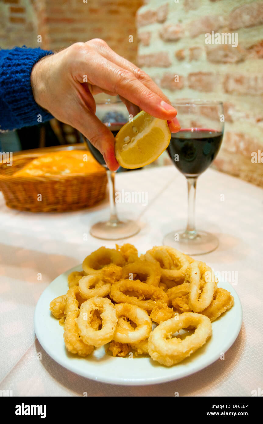 Mannes Hand Dressing gebratene Tintenfische mit Zitronensaft beträufeln. Stockfoto