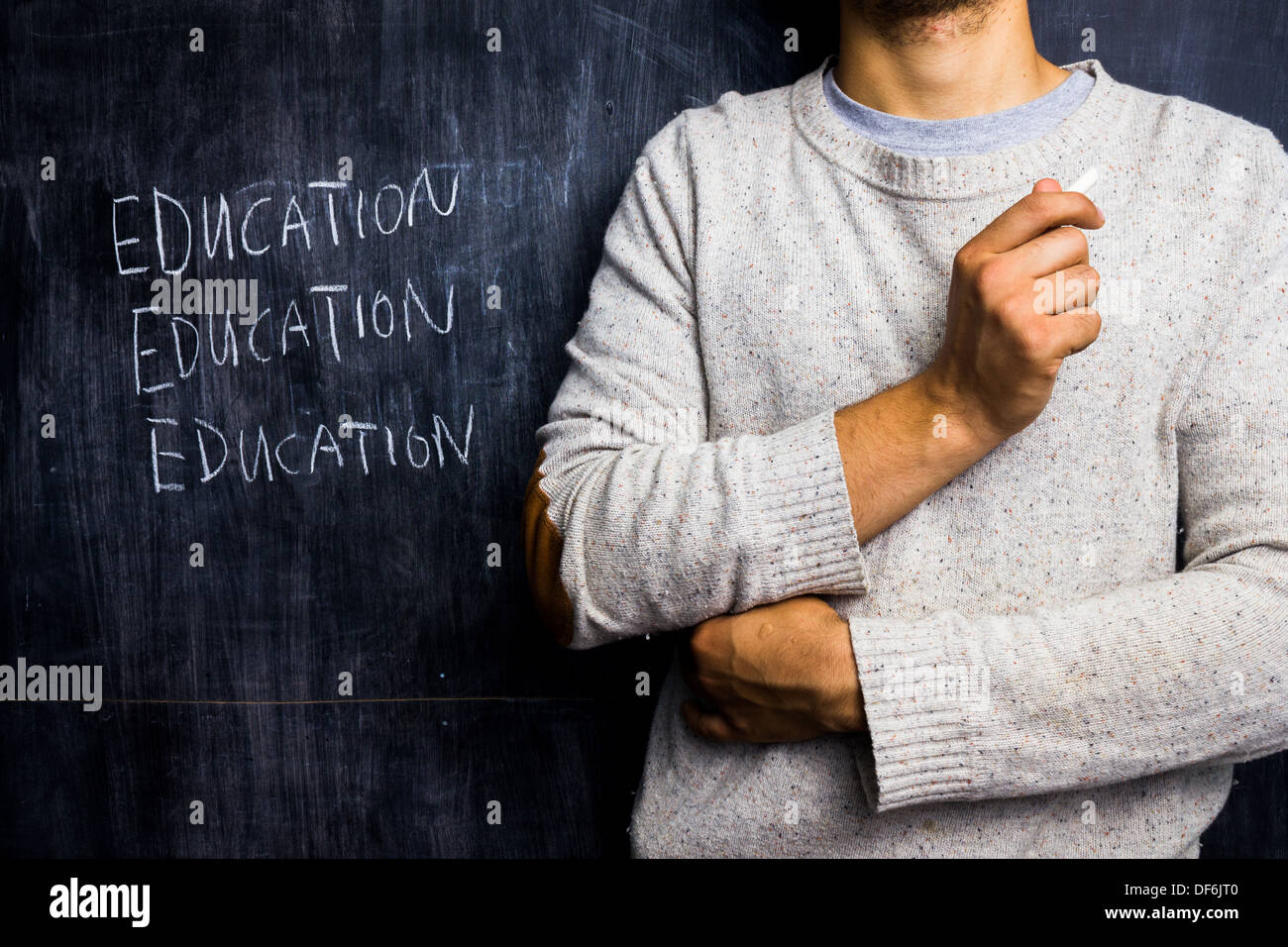 Junge männliche Lehrer von Blackboard mit dem Wort Bildung stehen wiederholt hinter ihm Stockfoto