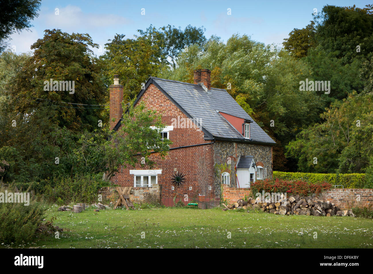 Das äußere eines kleinen isolierten Backstein-Cottage in einem Feld, umgeben von Bäumen in Suffolk, England. Stockfoto
