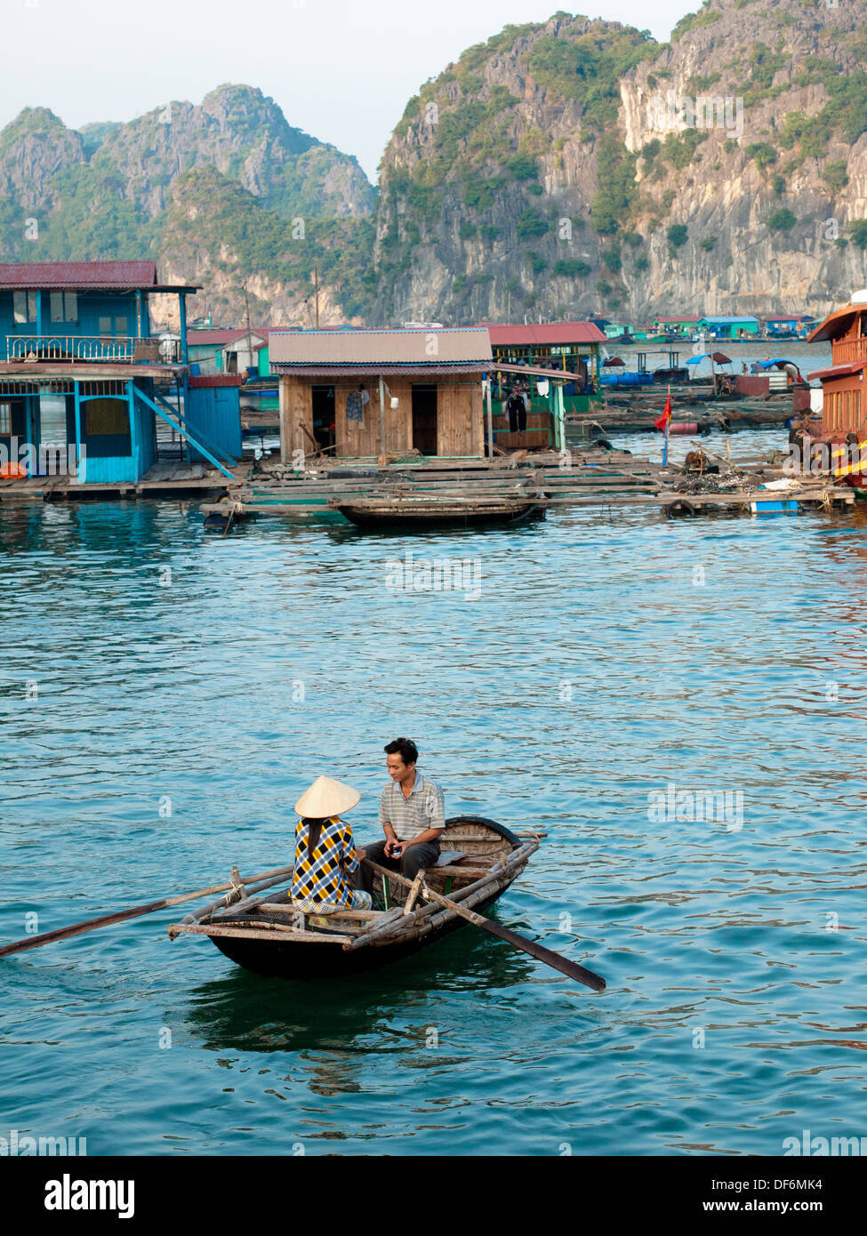 In der Nähe von einem schwimmenden Dorf von Cat Ba Insel im Lan Ha Bucht, Halong Bucht, Vietnam, vietnamesische Mann und Frau in einem Ruderboot. Stockfoto