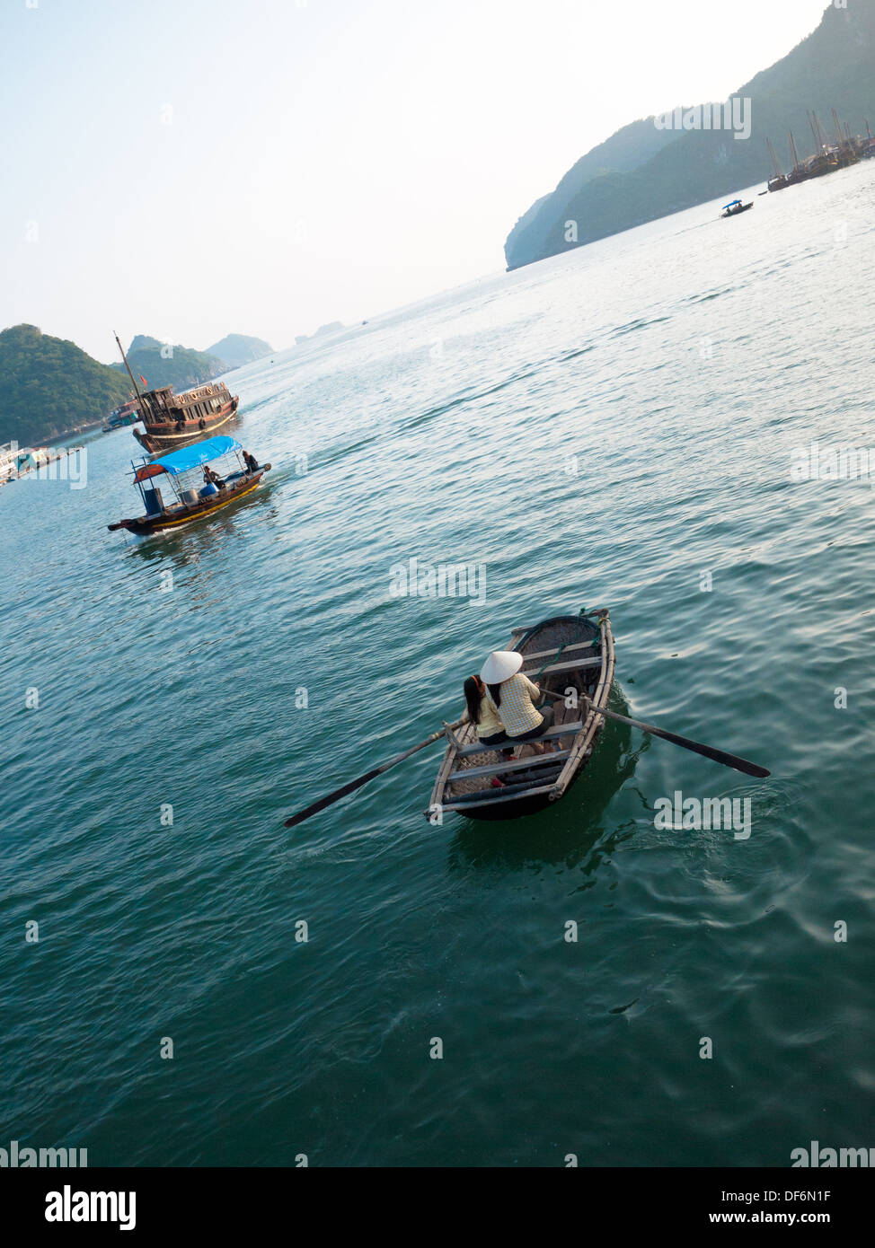 Eine Vietnamesin in einen konischen Hut und ein vietnamesisches Mädchen in einem Ruderboot aus Cat Ba Island in Lan-Ha-Bucht, Halong Bucht, Vietnam. Stockfoto