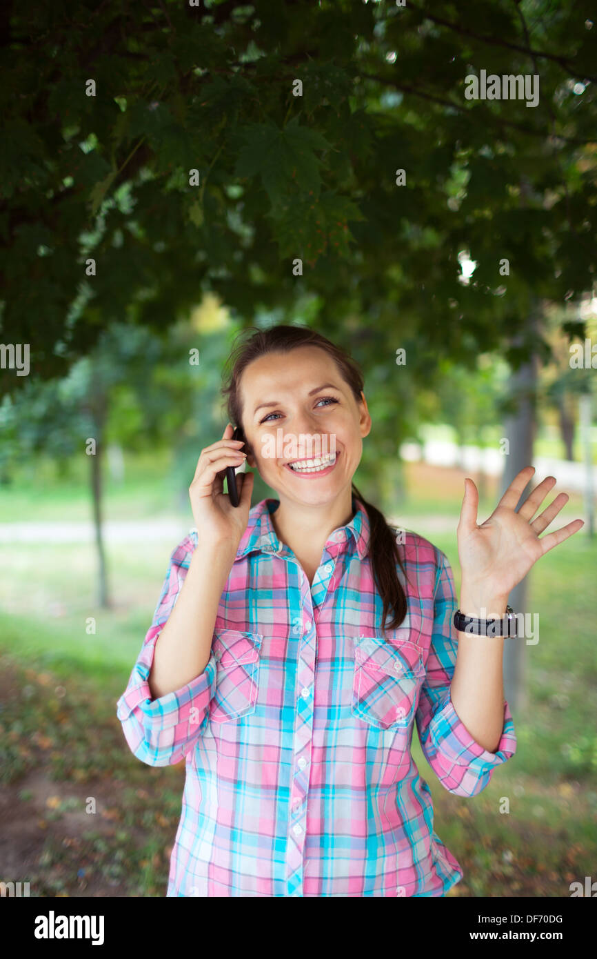 Porträt einer lächelnden jungen Frau in einem Park am Telefon sprechen Stockfoto