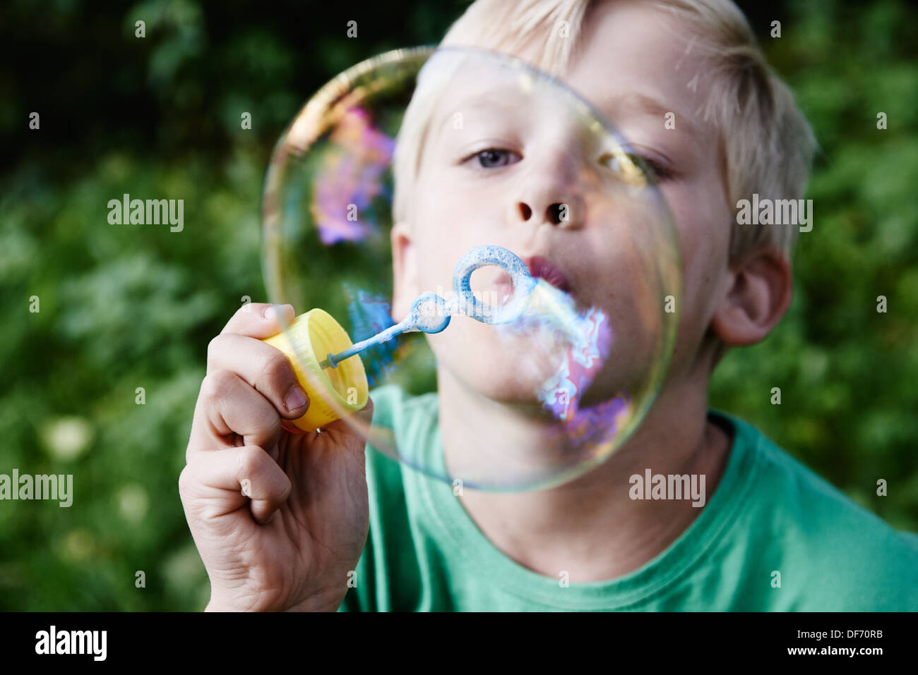 Kind blonde junge bläst und dabei Luftblasen im freien Stockfoto