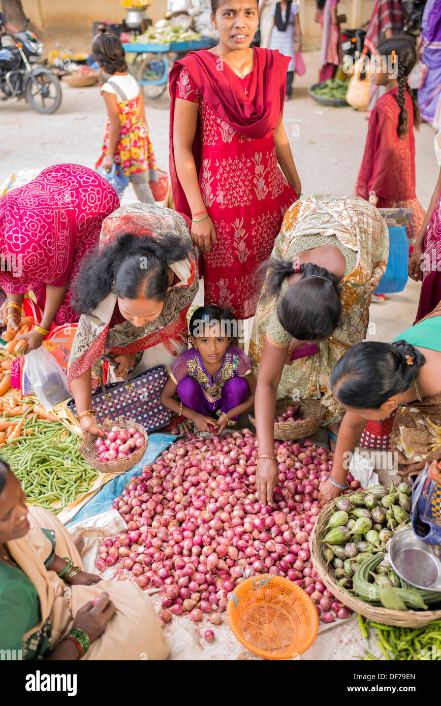 Indische Mädchen unter Müttern kaufen Gemüse aus einem Straßenmarkt. Puttaparthi, Andhra Pradesh, Indien Stockfoto