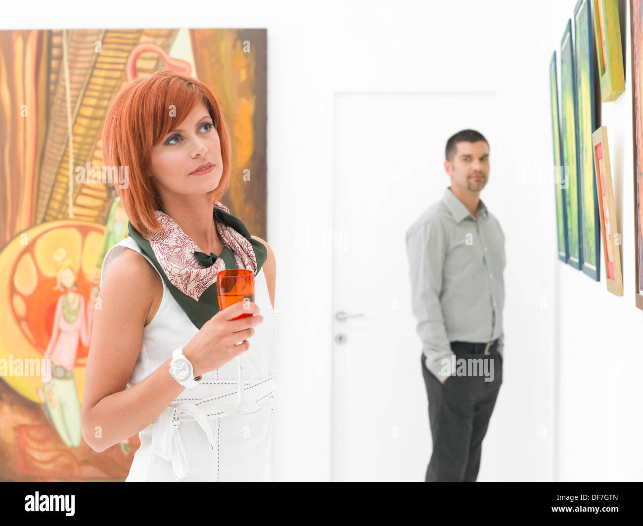 Mann, eine junge schöne rothaarige Frau in einer Kunstgalerie zu bewundern Stockfoto